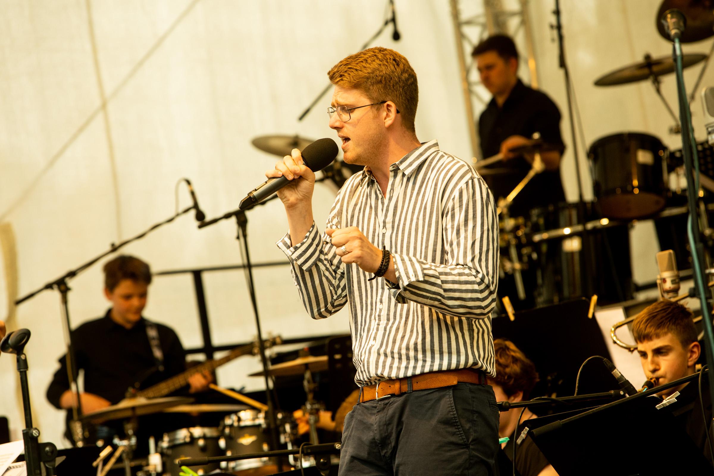 Junger Sänger steht mit Landesjugendjazzorchester Brandenburg auf einer Bühne