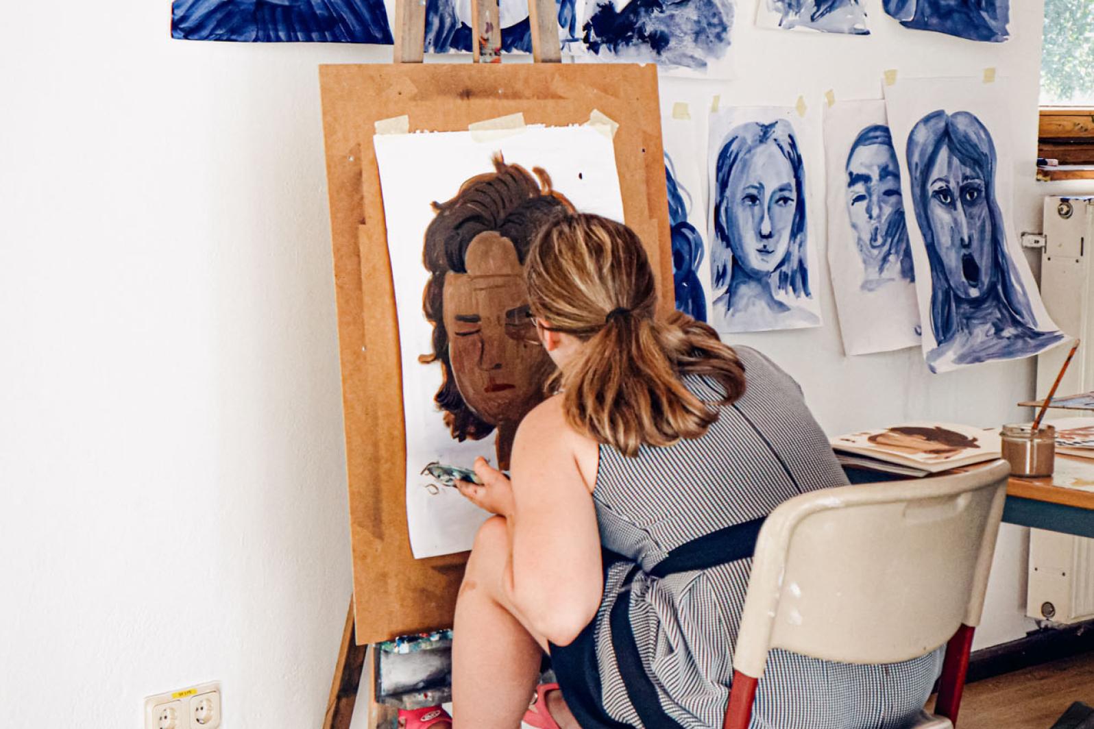 Mädchen malt auf Leinwand auf Staffelei