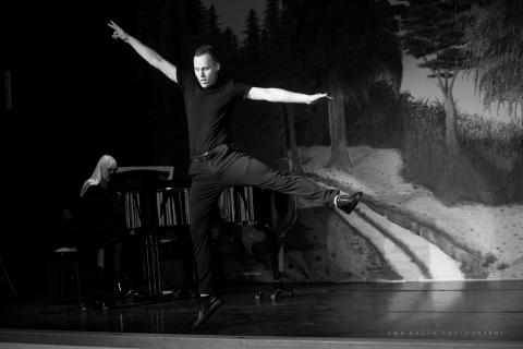 Musical-Performance von Elvis Kuklinski, schwarz/weiß, Sprung, Klavier im Hintergrund