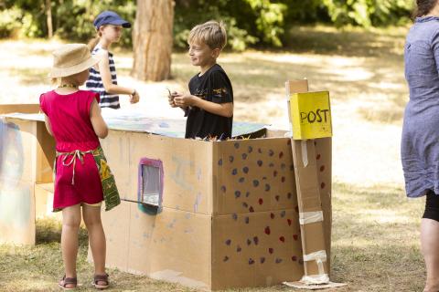 2 Kinder auf der Kunstwiese bzw. einer Post-Filiale aus Pappe beim Sound City Festival 2023 in Schwedt