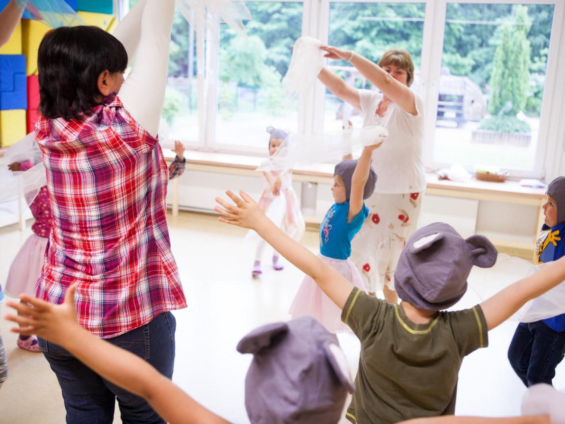 Eine Gruppe Erwachsene und Kinder tanzen mit Tüchern